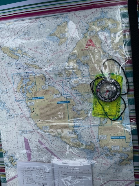 A map of the Salish Sea around San Juan Island. its' sealed in a ziplock for water protection, and also includes a compass and a small notebook noting the expected tides.
